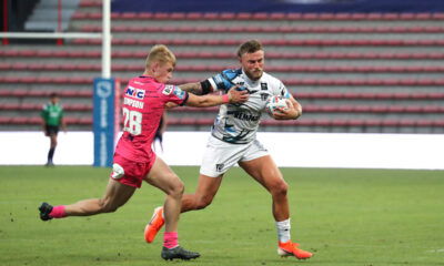 Max Simpson, in a white Leeds Rhinos strip, holds off Toulouse's Chris Hankinson, who wears red.