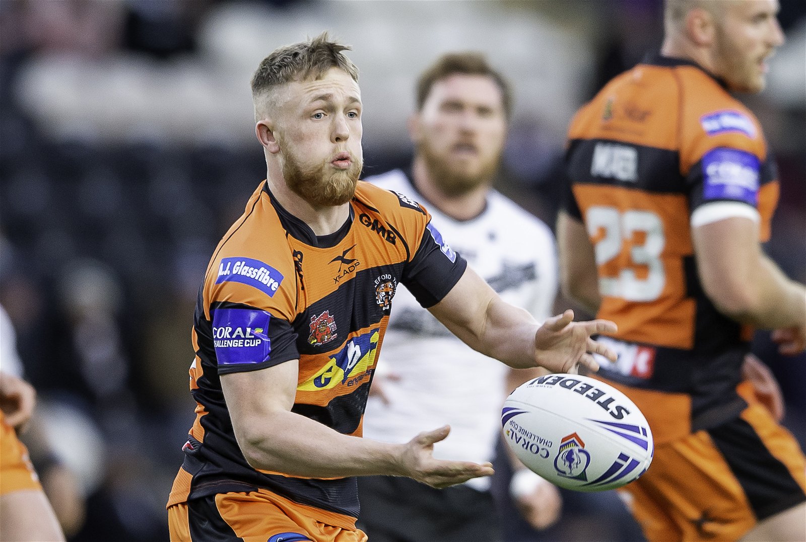 Cory Aston playing for Castleford Tigers in an orange and black horizontal-striped kit.