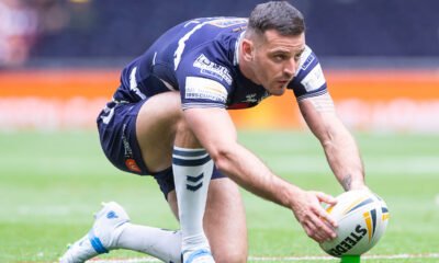 Craig Hall takes a kick for Featherstone Rovers. The ball is on the kicking tee and he leans down to position it, looking up.