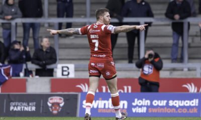 Marc Sneyd celebrates a drop-goal against Salford. He wears a red shirt and can be seen, from behind, with arms outstretched.