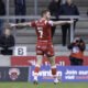 Marc Sneyd celebrates a drop-goal against Salford. He wears a red shirt and can be seen, from behind, with arms outstretched.