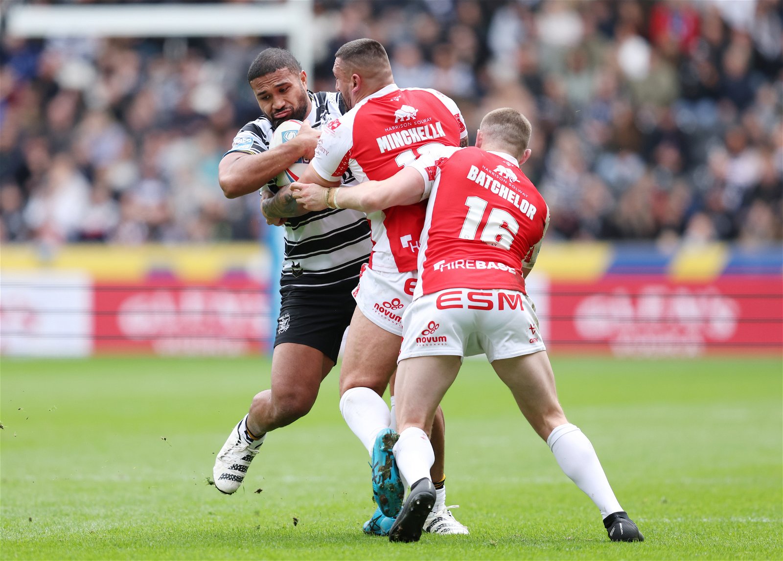 Hull FC's (black and white stripes)Chris Satae is tackled by Hull Kingston Rovers' (red) Elliot Minchella and James Batchelor