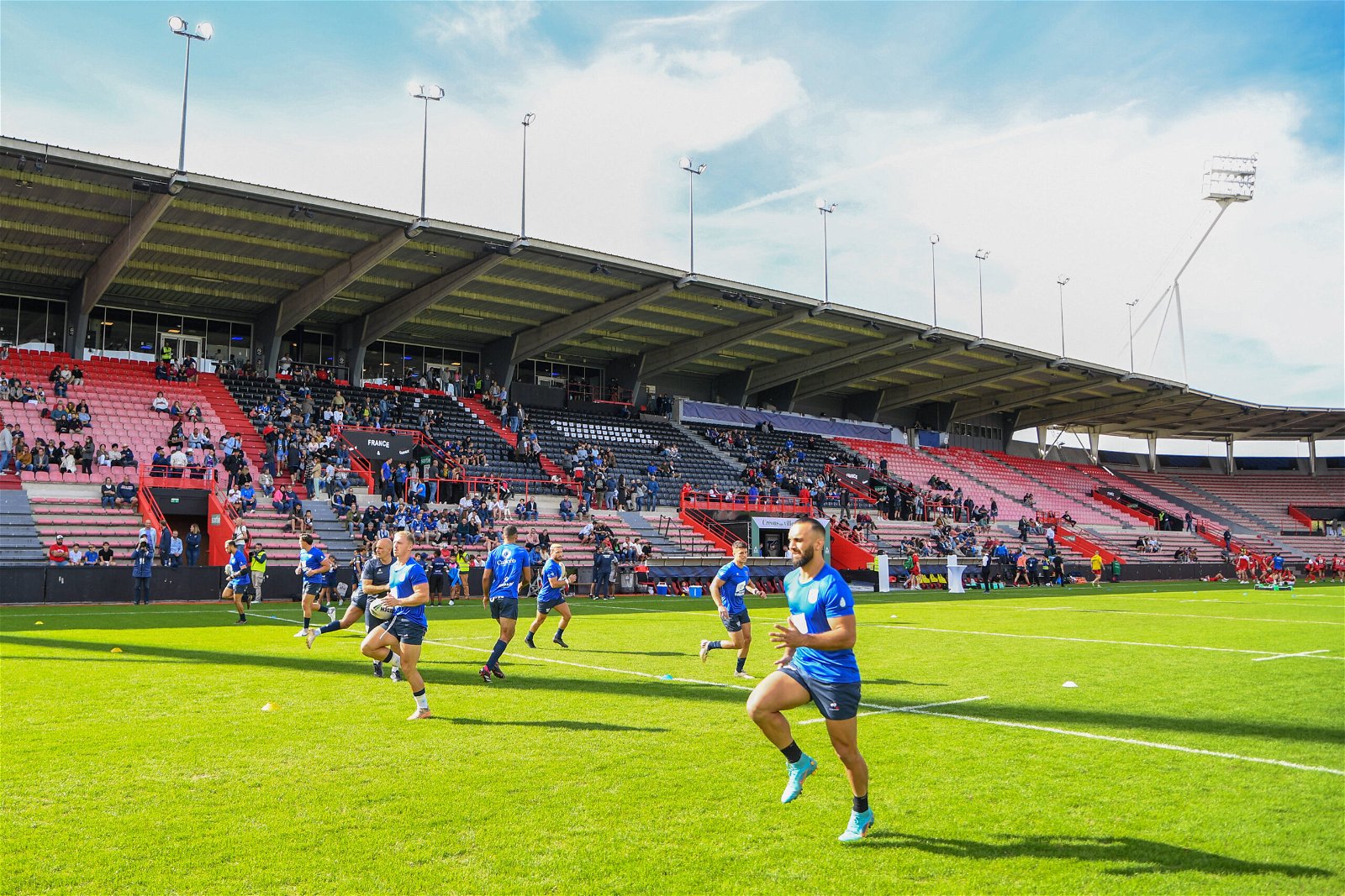 Players warm up before a Championship match at the Stade Ernest-Wallon, which has red and black seats. It's large, but yet to fill up with fans.