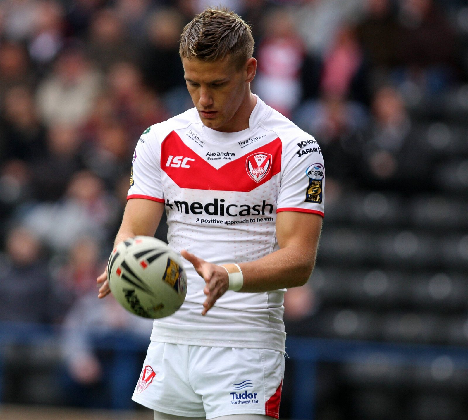 Jamie Foster, in St Helens kit, looks down at the rugby ball.