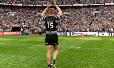 Chris Green of Hull FC, seen from behind, wearing traditional black and white, applauds fans at Wembley Stadium