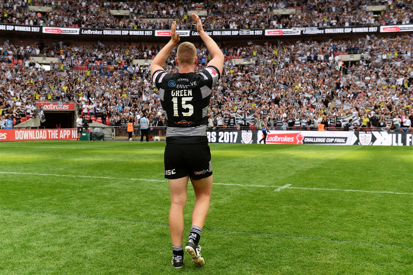 Chris Green of Hull FC, seen from behind, wearing traditional black and white, applauds fans at Wembley Stadium
