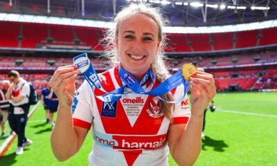 Jodie Cunningham of St Helens celebrates winning the Challenge Cup at Wembley, holding her medal to the camera.