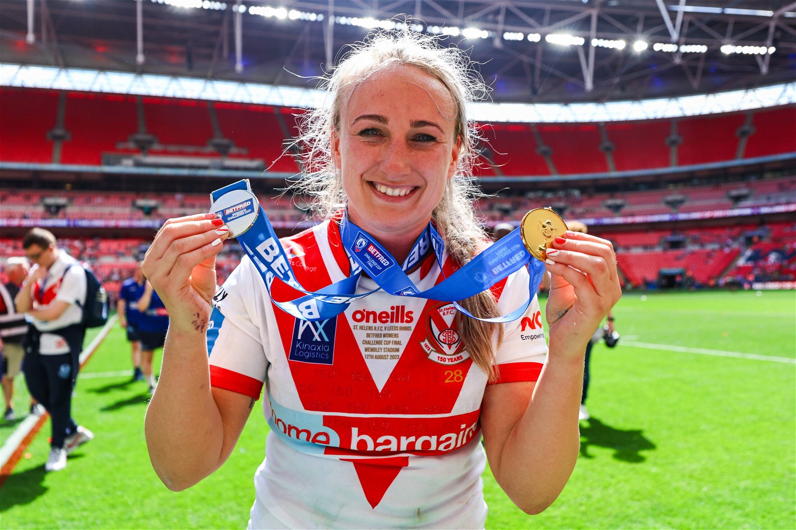 Jodie Cunningham of St Helens celebrates winning the Challenge Cup at Wembley, holding her medal to the camera.