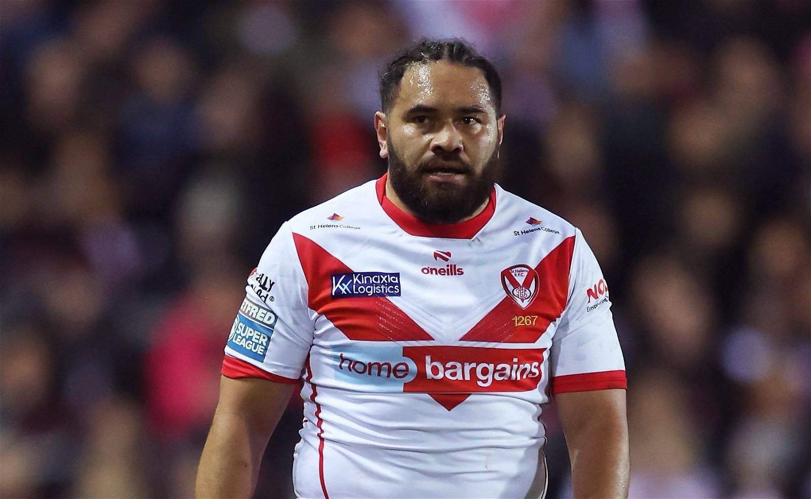 Konrad Hurrell is wearing the St Helens shirt. Of course, it's white with a red V, and there's a thin red line down the sides. The collar and sleeve cuffs are red. The Home Bargains logo on it is huge.