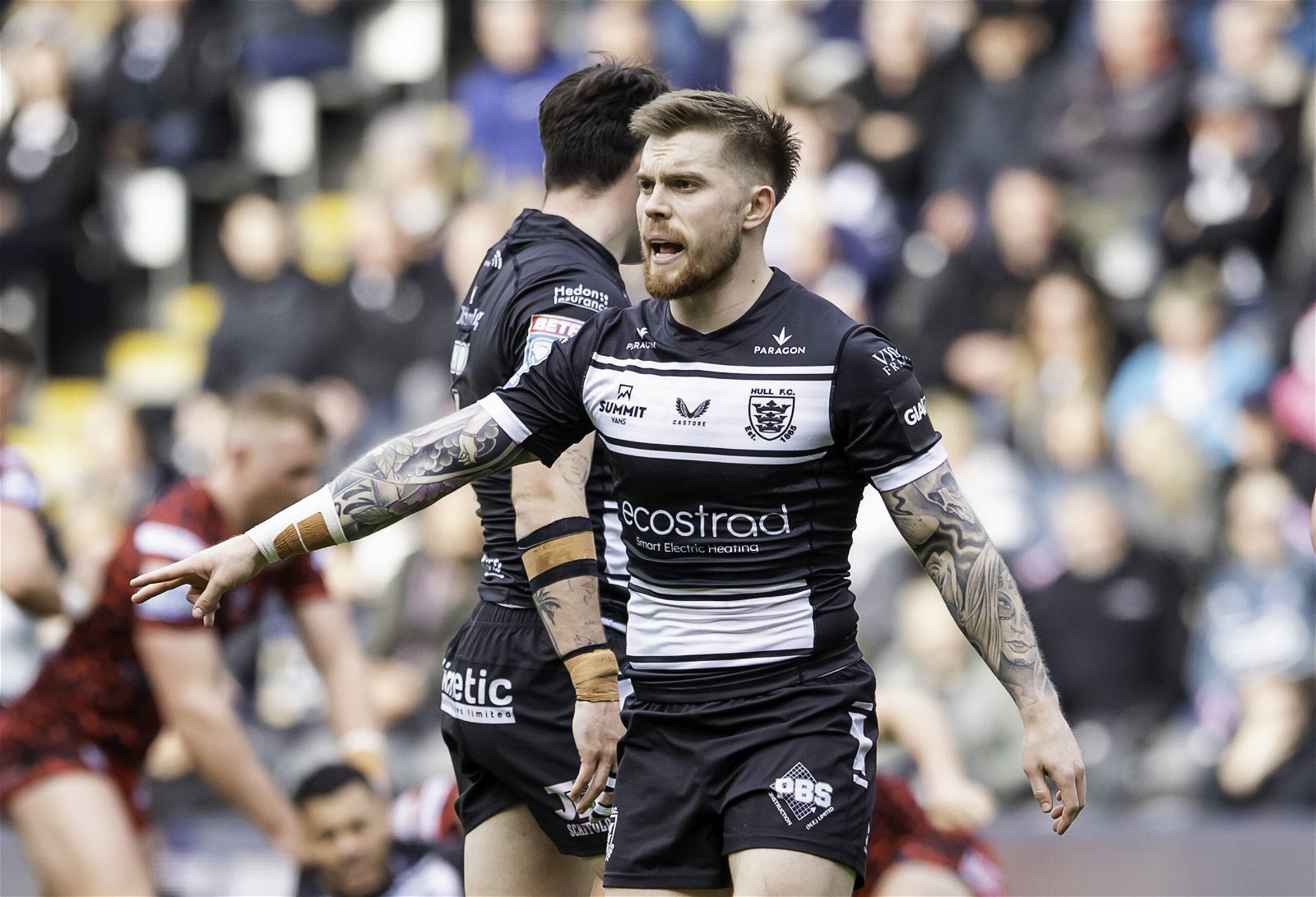 Morgan Smith, wearing Hull FC's new shirt. It's predominantly black, with a white stripe across where the badge is, and one right near the bottom as well. Where there should usually be a middle stripe, the Ecostrad logo is. White sleeve cuffs finish it off, as well as the Summit Vans and Castore logos in black on the top white stripe, and above that, the Paragon logo in white.
