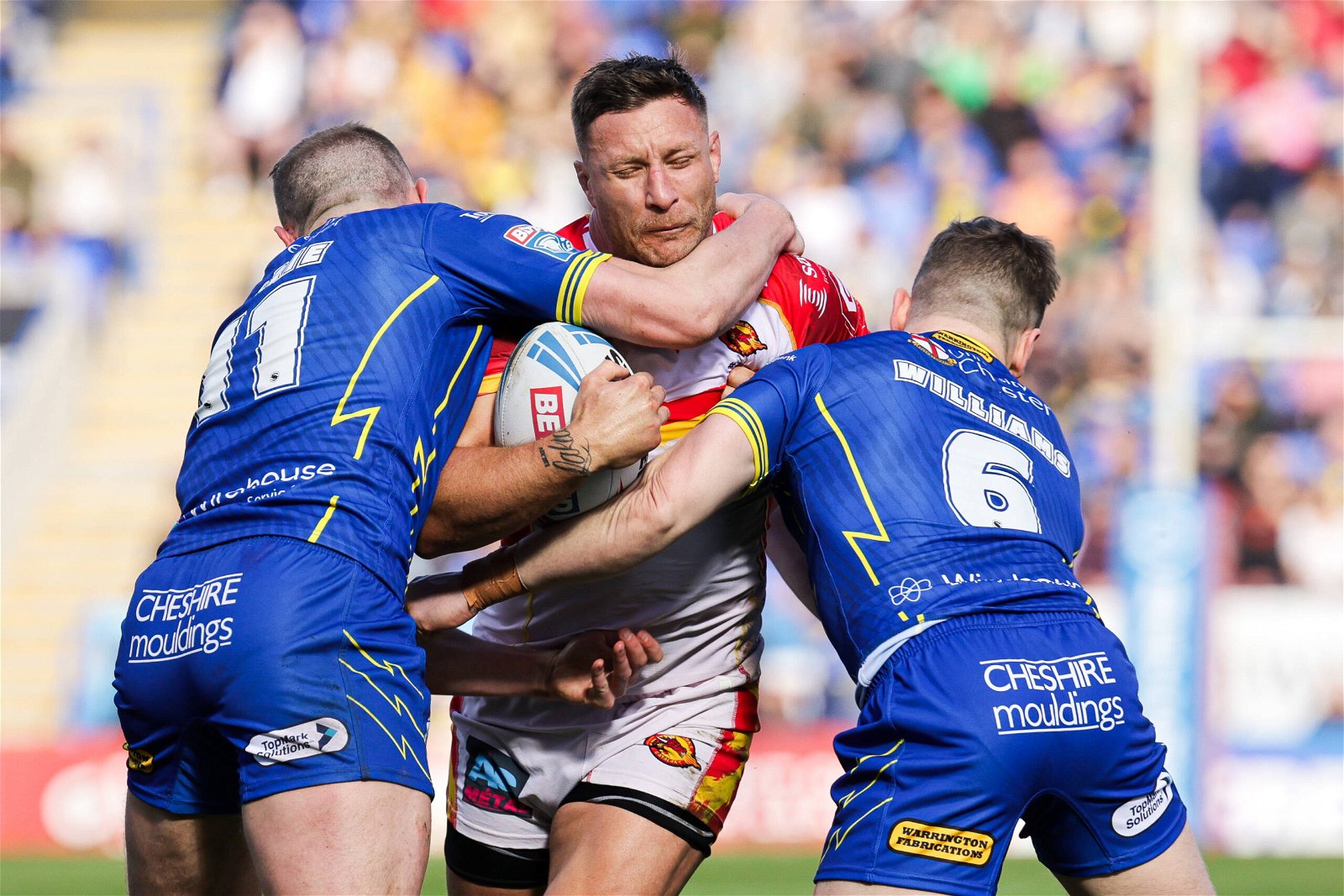 Catalans' Tariq Sims is tackled by Warrington's Ben Currie and George Williams.