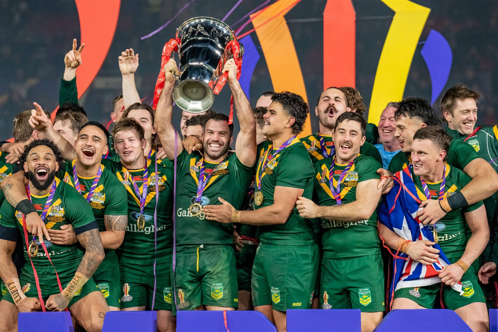 As an Australia player, James Tedesco, of NRL side Sydney Roosters, lifts the Rugby League World Cup 2021 trophy with teammates.