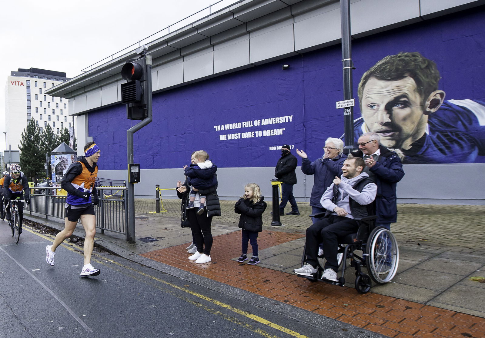 Kevin Sinfield MBE runs to greet Rob Burrow in front of a Rob Burrow mural.