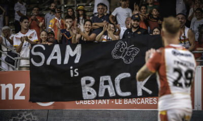 Sam Tomkins looks at a sign saying "Sam is back". Catalans Dragons